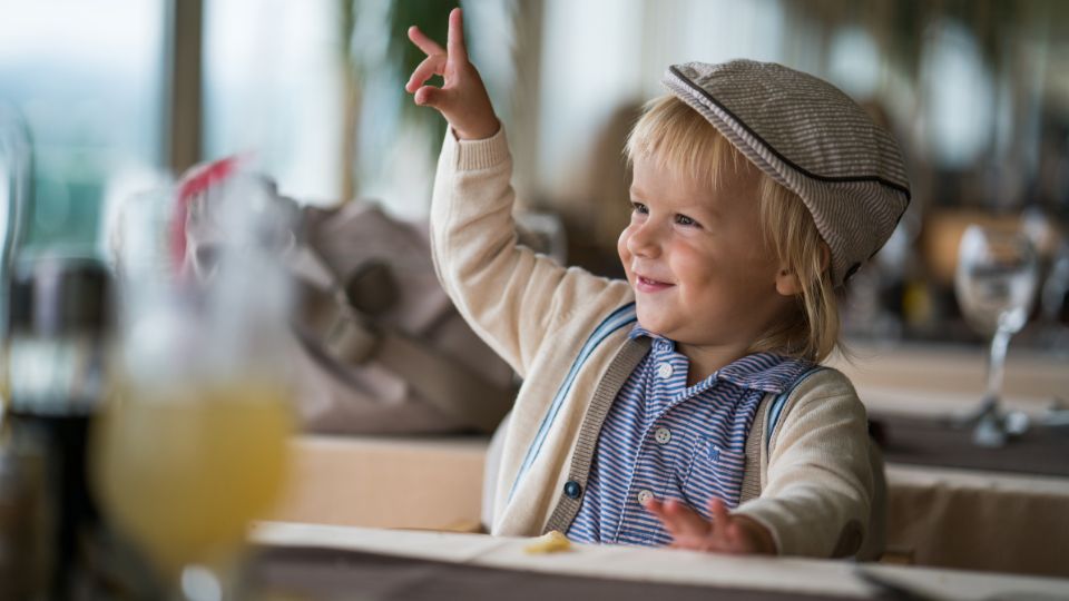 enfant blond français souriant levant la main